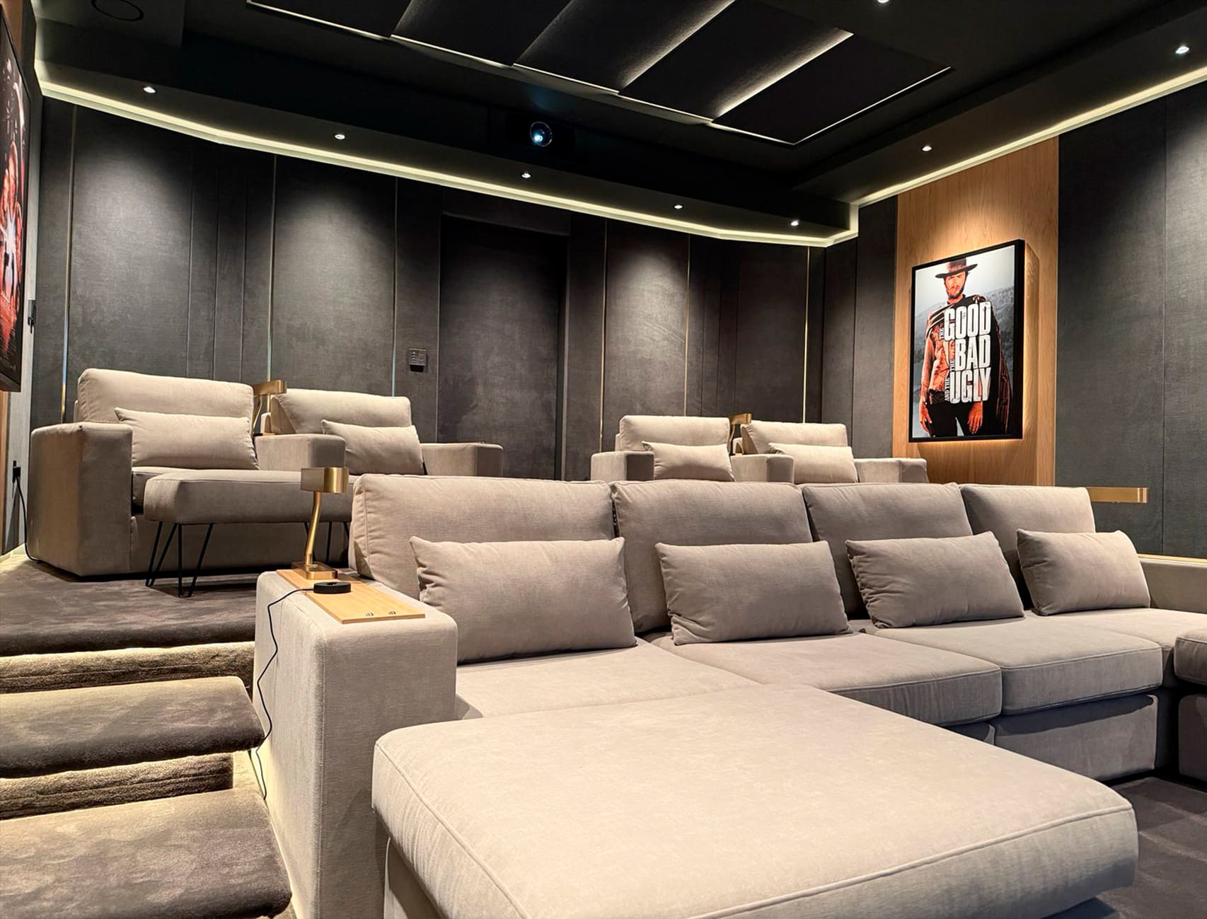 Luxury home cinema with large projection screen, acoustic wall panels, and plush seating, designed by Sinemas using Lyngdorf Audio for an immersive cinematic experience.